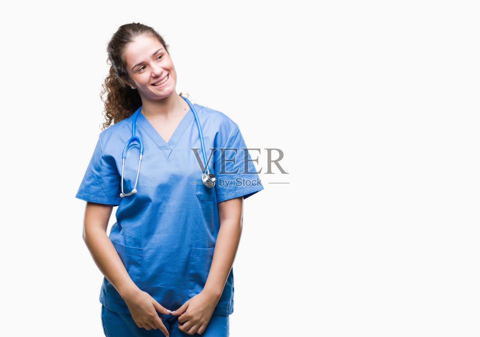 年轻的黑发医生女孩穿着护士或外科医生制服在孤立的背景看向一边面带微笑，自然的表情。自信的笑。照片摄影图片