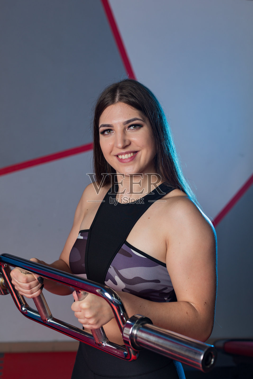 美丽的女孩在健身房的地板上用杠铃锻炼肱二头肌照片摄影图片