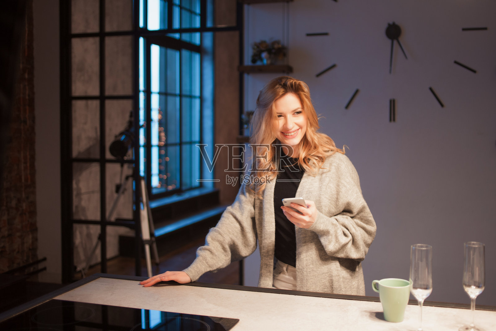 年轻漂亮的女人在厨房里拿着智能手机。在网上寻找烹饪食谱。照片摄影图片