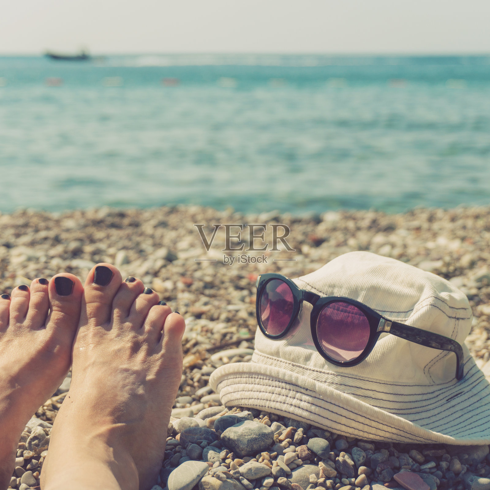 女人的脚，帽子和太阳镜在海滩上照片摄影图片