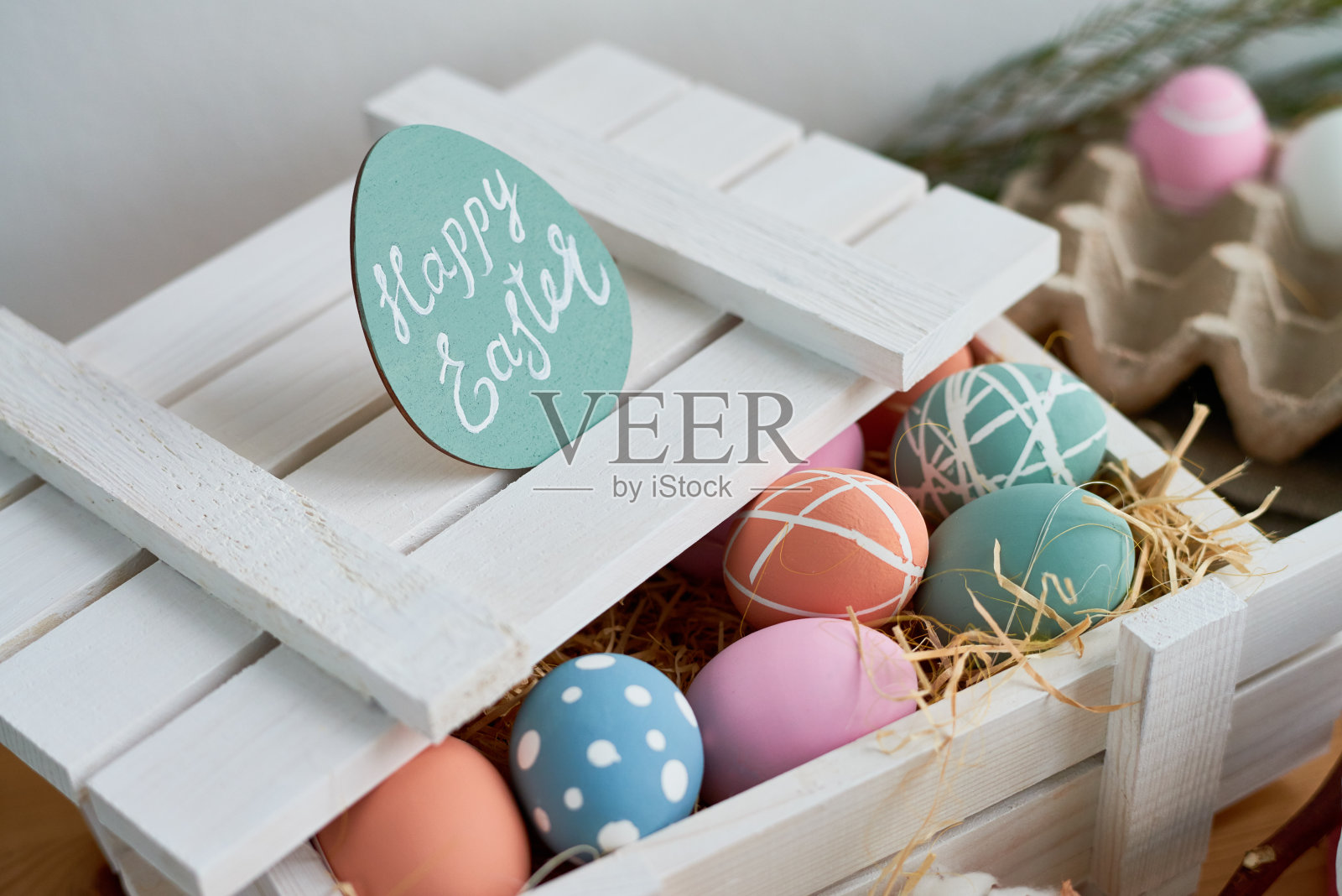 复活节装饰:特写的白色木制盒子与打开的封面满是创意绘制的鸡蛋在干草，复活节快乐卡照片摄影图片