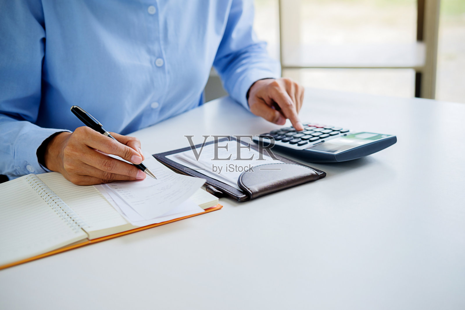 拿着账单和计算器的女人。女人在办公室里用计算器计算账单。计算成本。照片摄影图片