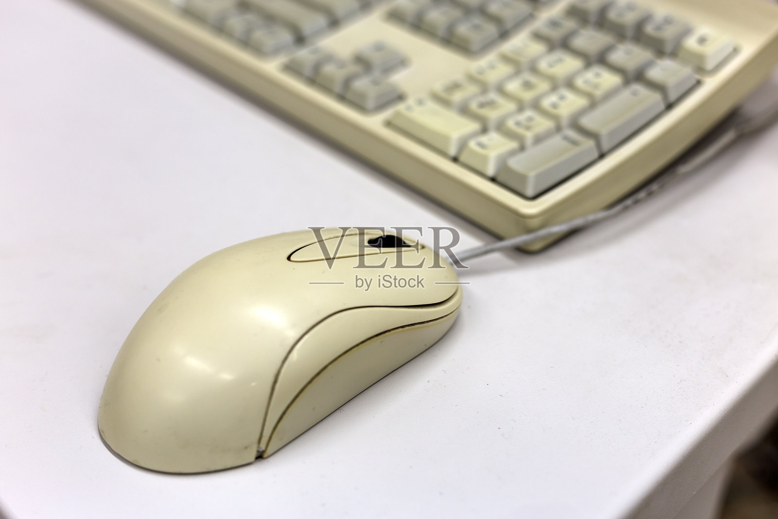 模糊的PC键盘背景上的白色鼠标的特写。现代技术、信息和通信理念。照片摄影图片