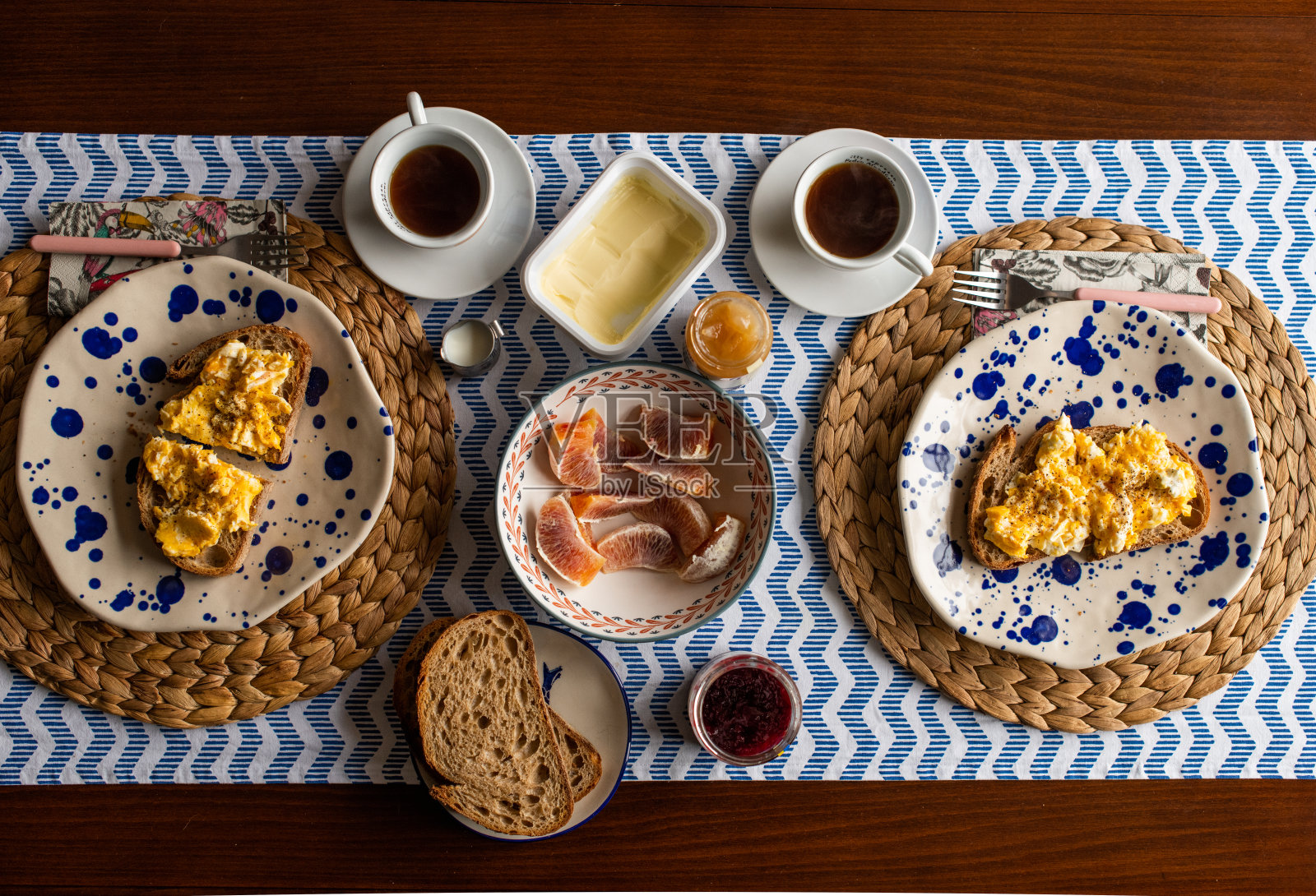 炒鸡蛋和烤面包。早餐的餐桌上有血橙、咖啡、果酱和黄油照片摄影图片