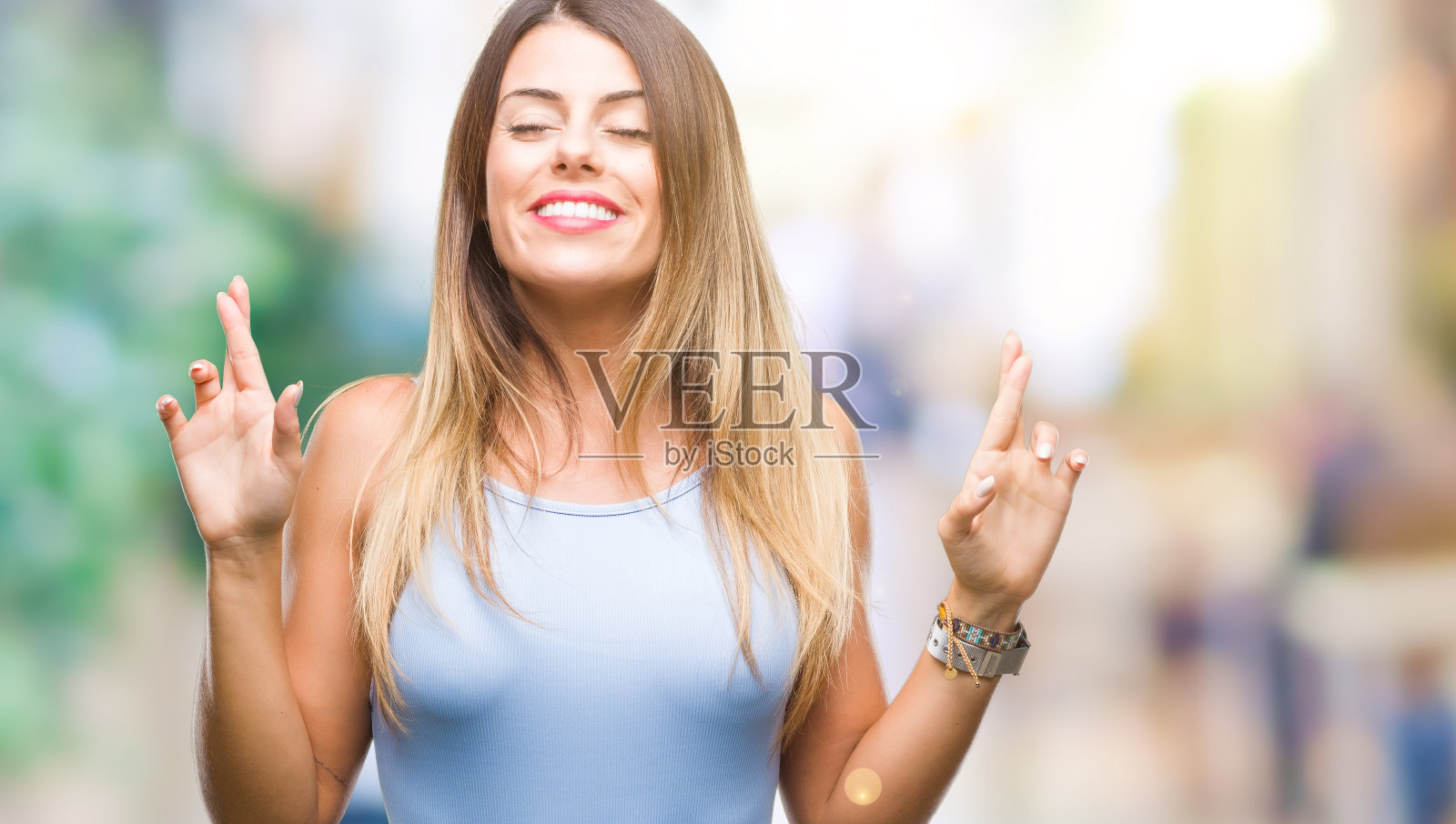 年轻美丽优雅的女商人在孤立的背景微笑交叉手指希望和闭上眼睛。运气和迷信的概念。照片摄影图片