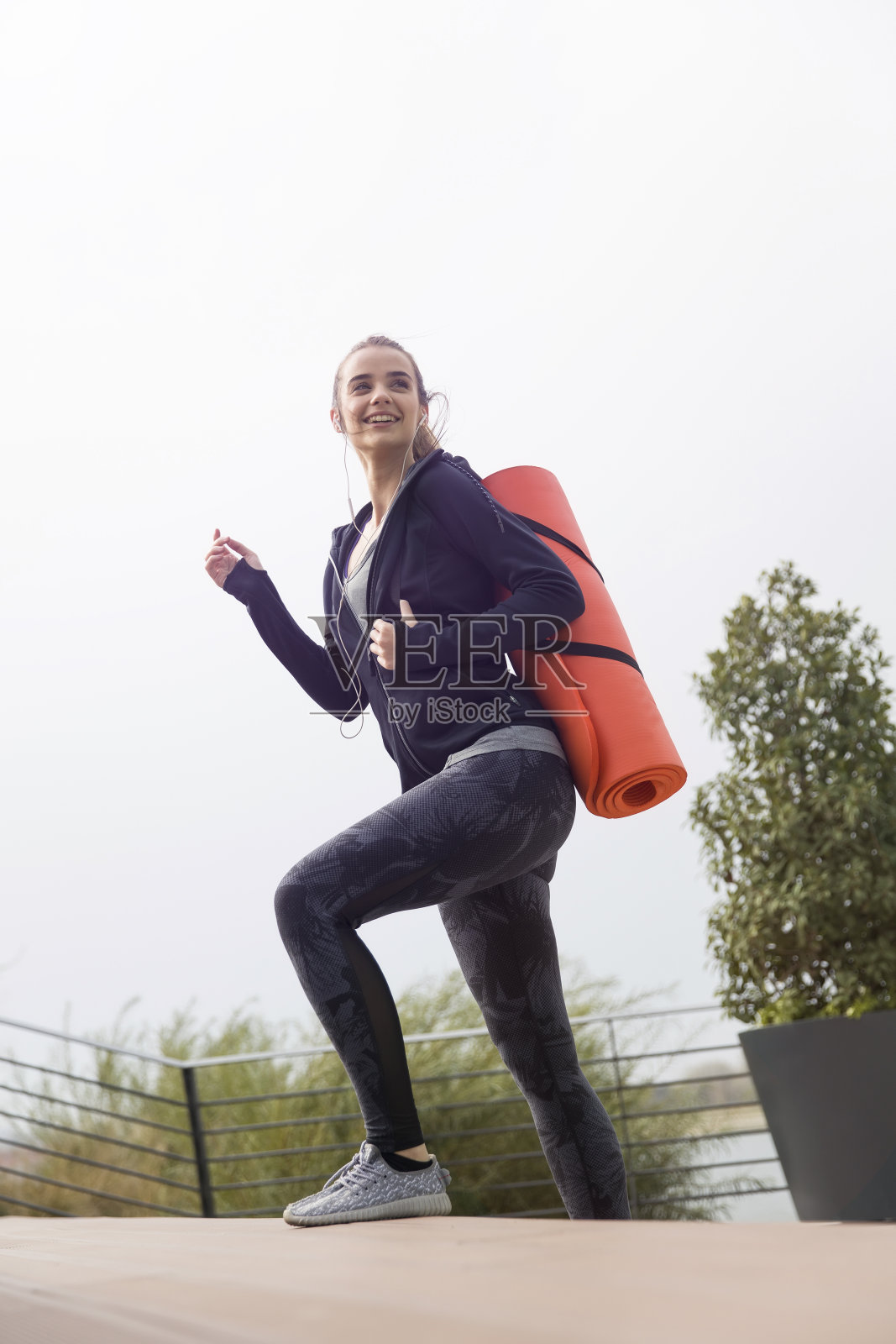 背着垫子走路的健身女性照片摄影图片