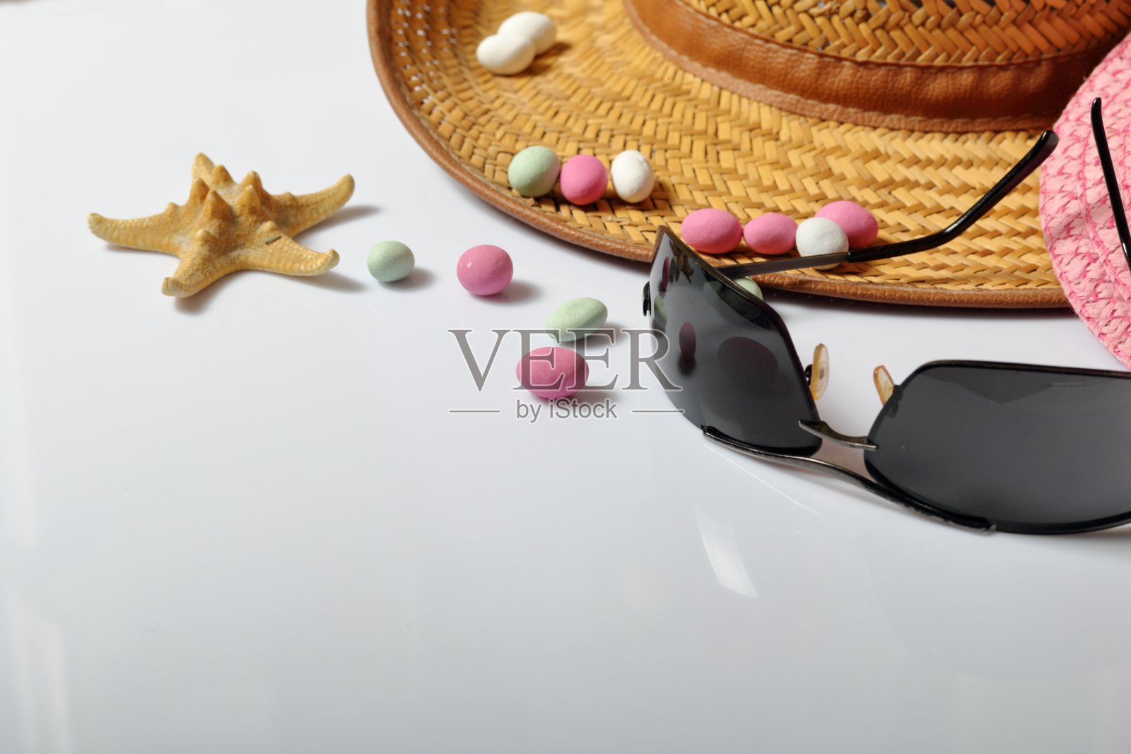 暑假配件。太阳帽，太阳镜，彩色鹅卵石和海星在白色的背景。照片摄影图片