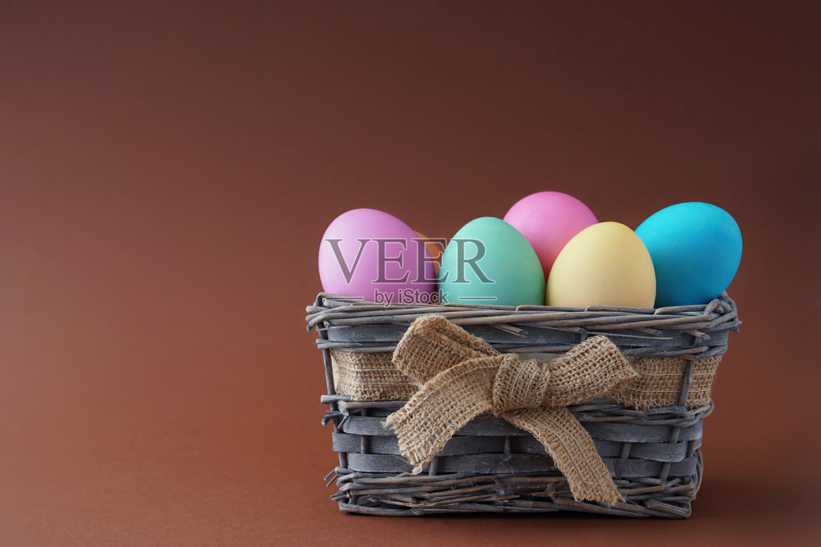复活节快乐，把染过颜色的鸡蛋放在篮子里以单色为背景。照片摄影图片