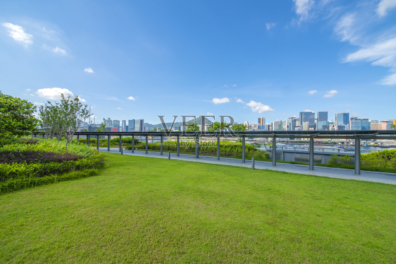 市中心现代公园的玻璃走道和草坪在蓝天白云下。照片摄影图片