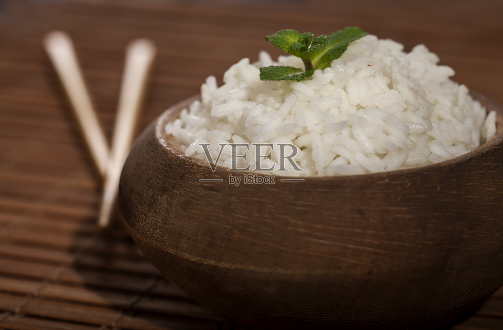 用筷子夹在木碗里把白米煮熟，放在竹木上。照片摄影图片