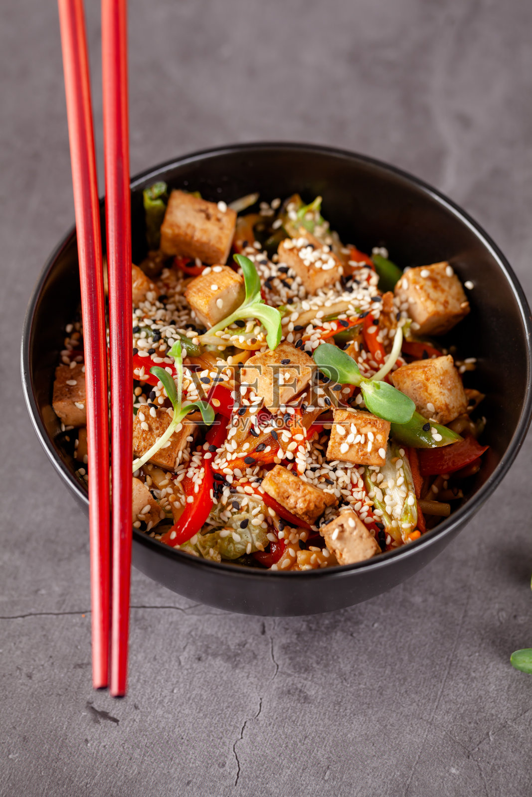 日本料理的概念。素菜面条豆腐奶酪和蔬菜在黑色陶瓷盘子。红色中国。本空间照片摄影图片