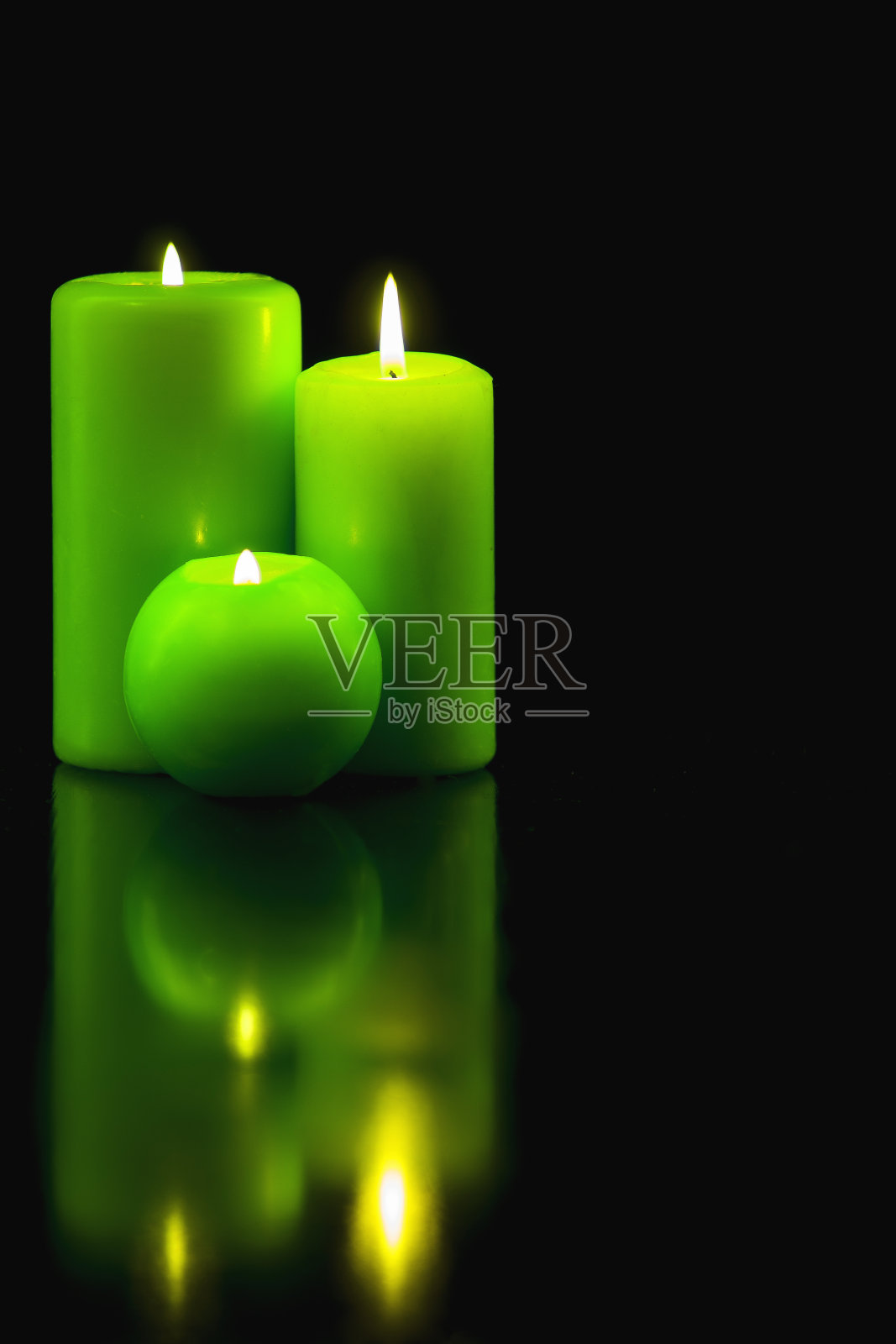 在黑色的背景上点燃绿色的蜡烛照片摄影图片