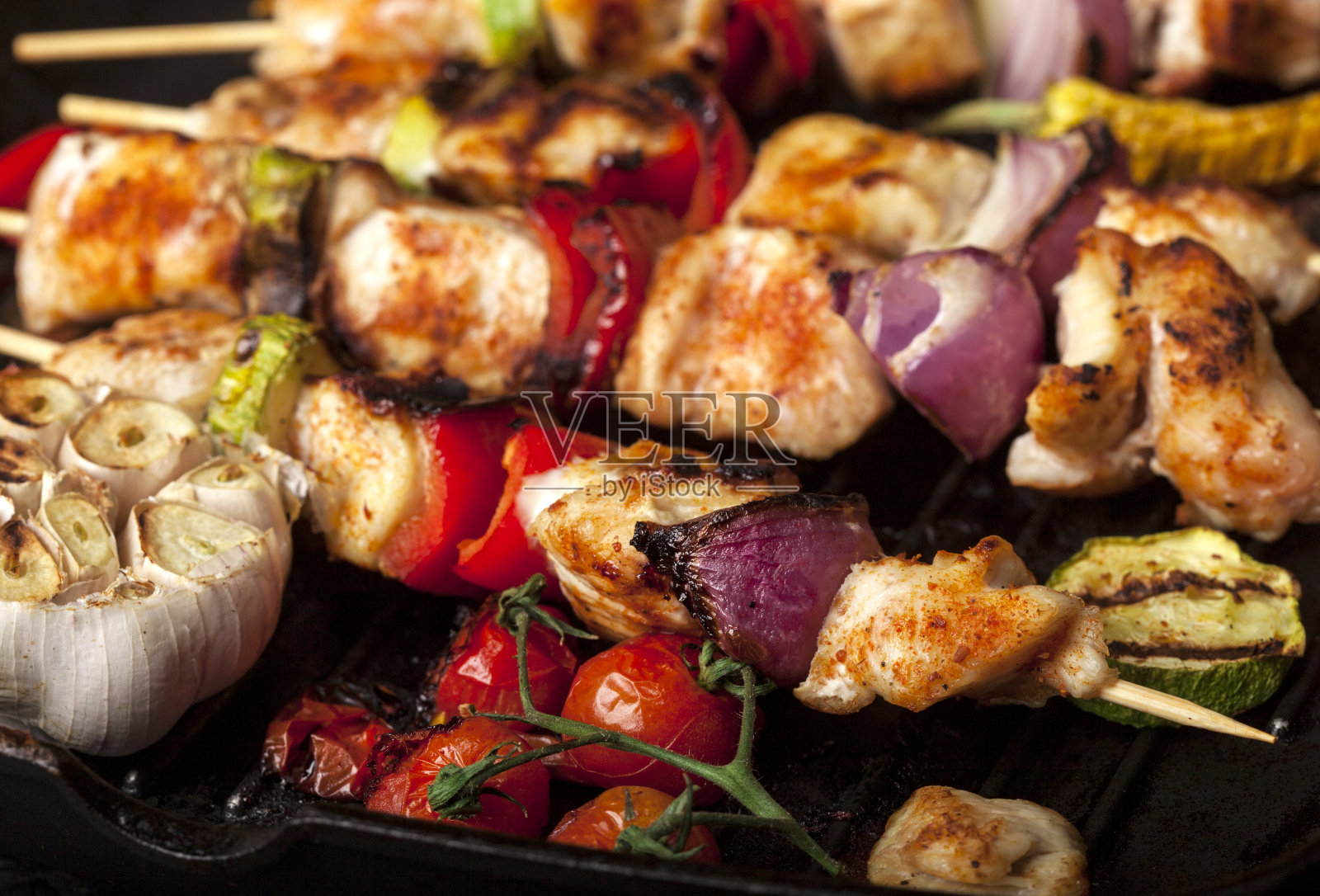 烤鸡串与香料和蔬菜在平底锅，在黑色背景照片摄影图片