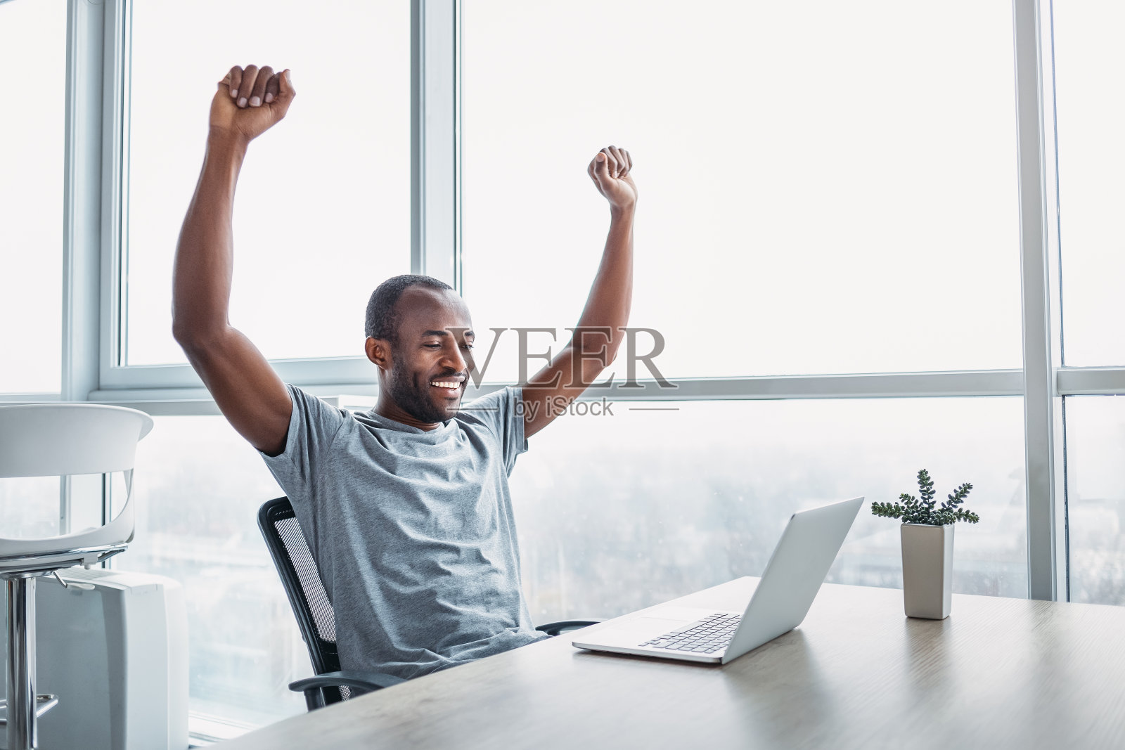 年轻的商人在宽敞明亮的办公室里用笔记本电脑工作。照片摄影图片