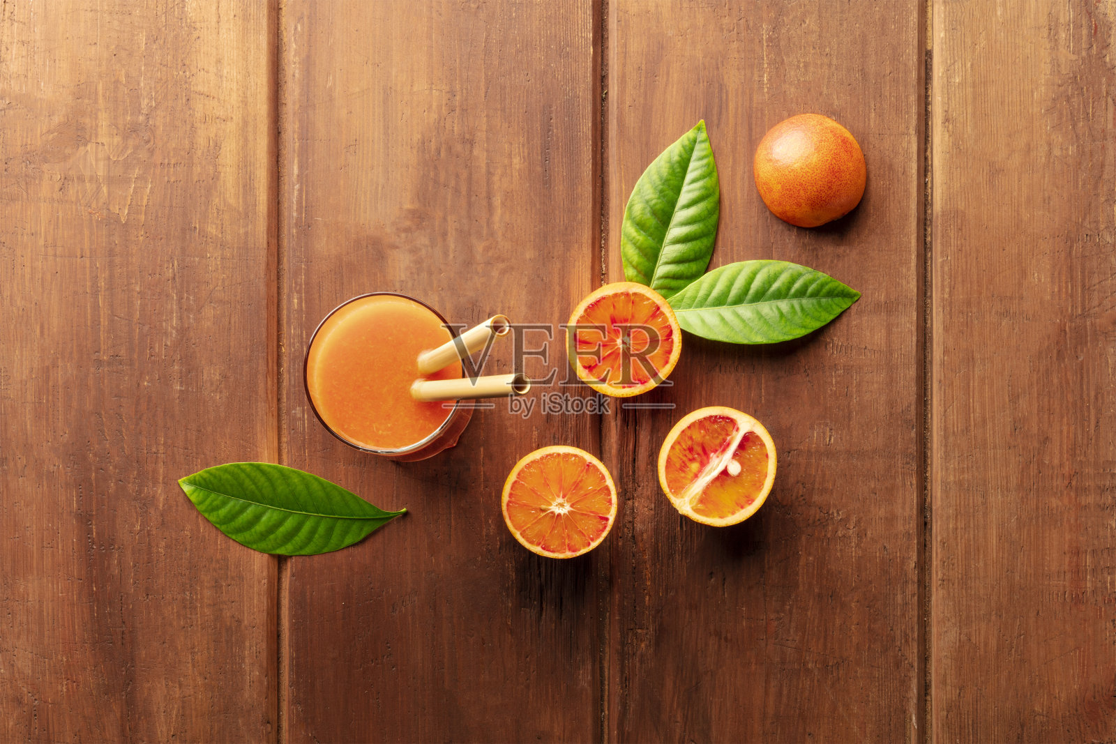 一杯新鲜的橙汁，配上血橙、绿叶和两根竹吸管，从上面拍摄，背景是黑色的乡村木色，有一个地方可以用来写文字照片摄影图片