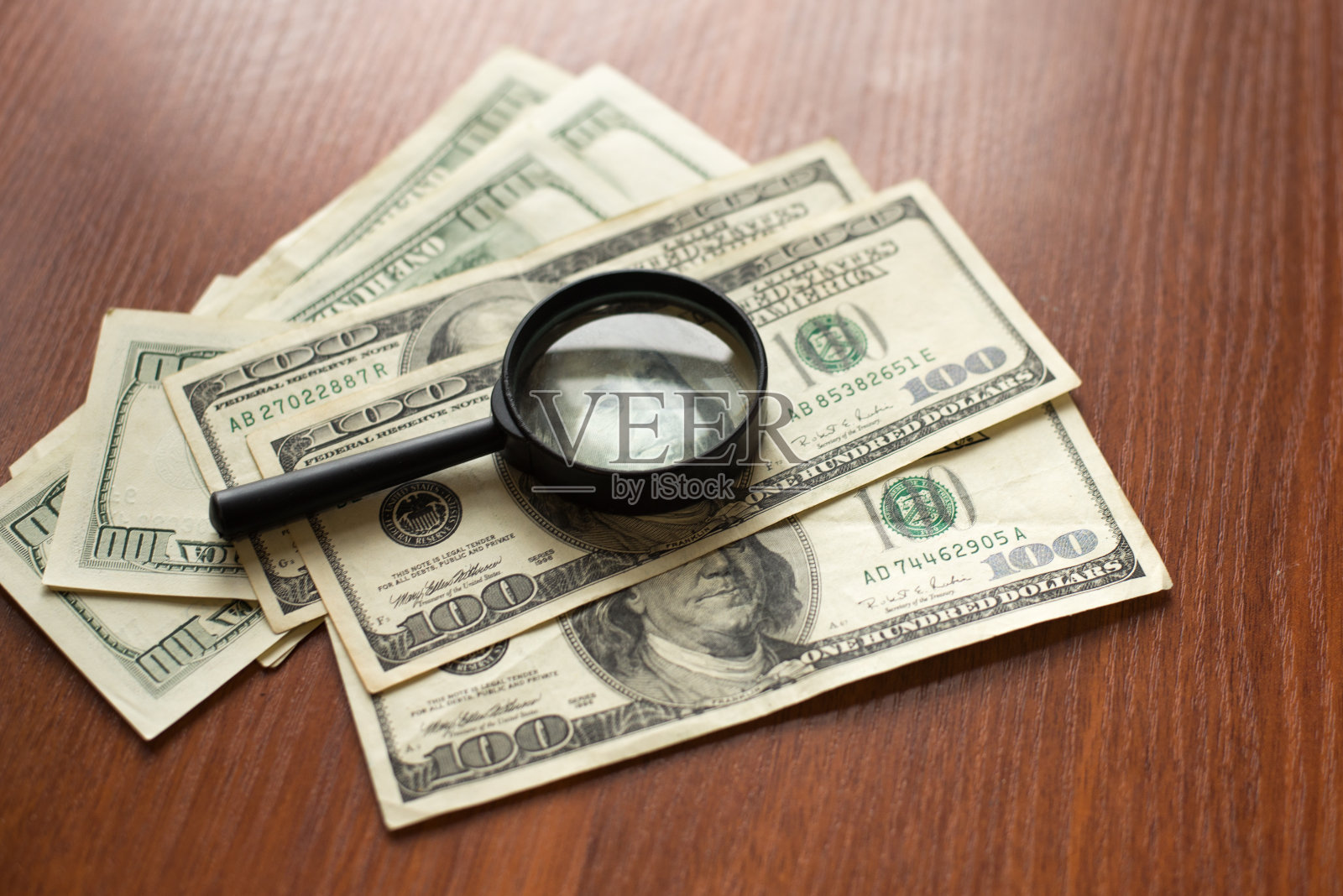 放大镜躺在美元上的木头背景上照片摄影图片