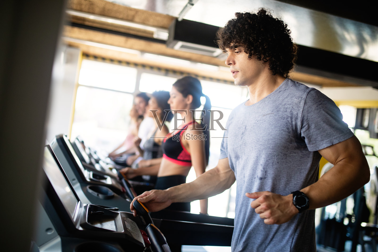 年轻人在健身俱乐部的跑步机上跑步。照片摄影图片