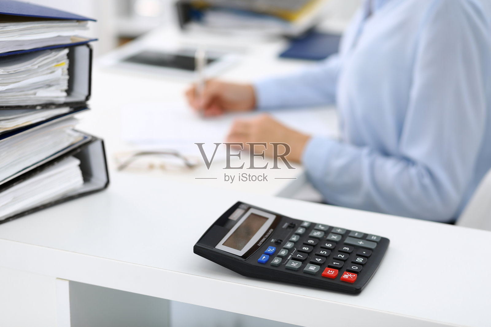 计算器和装订纸等着由女商人或簿记员在模糊中处理。内部审计和税务概念照片摄影图片