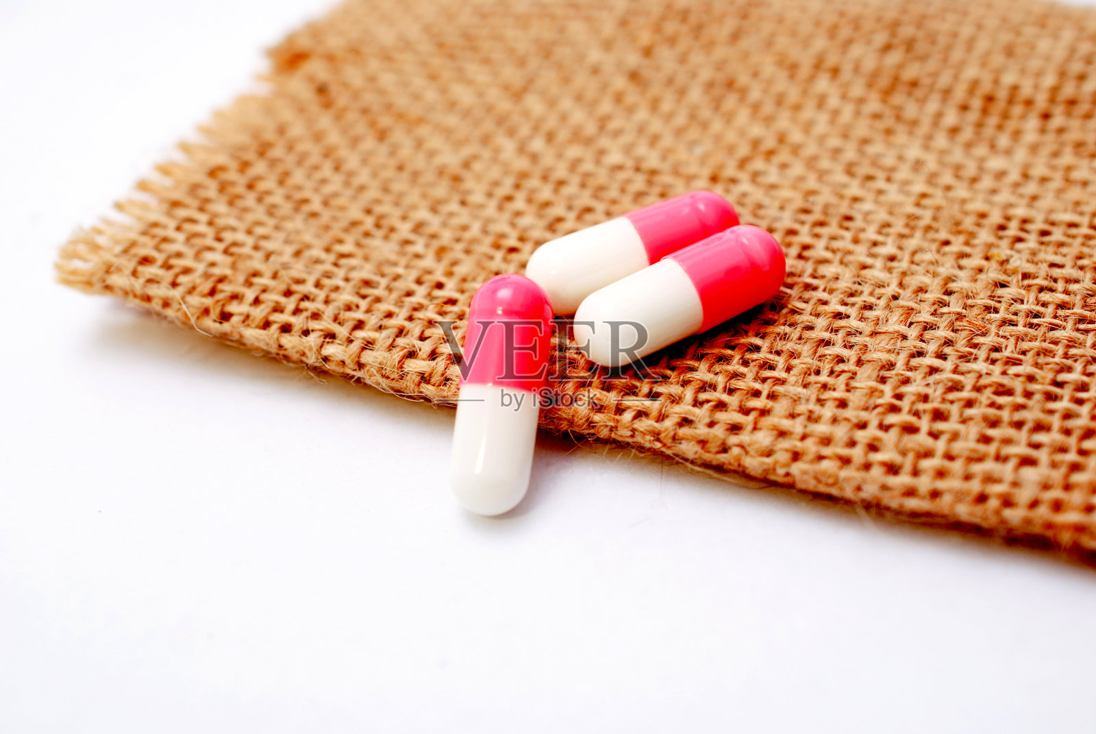 白色粉红色的胶囊在小黄麻的背景照片摄影图片