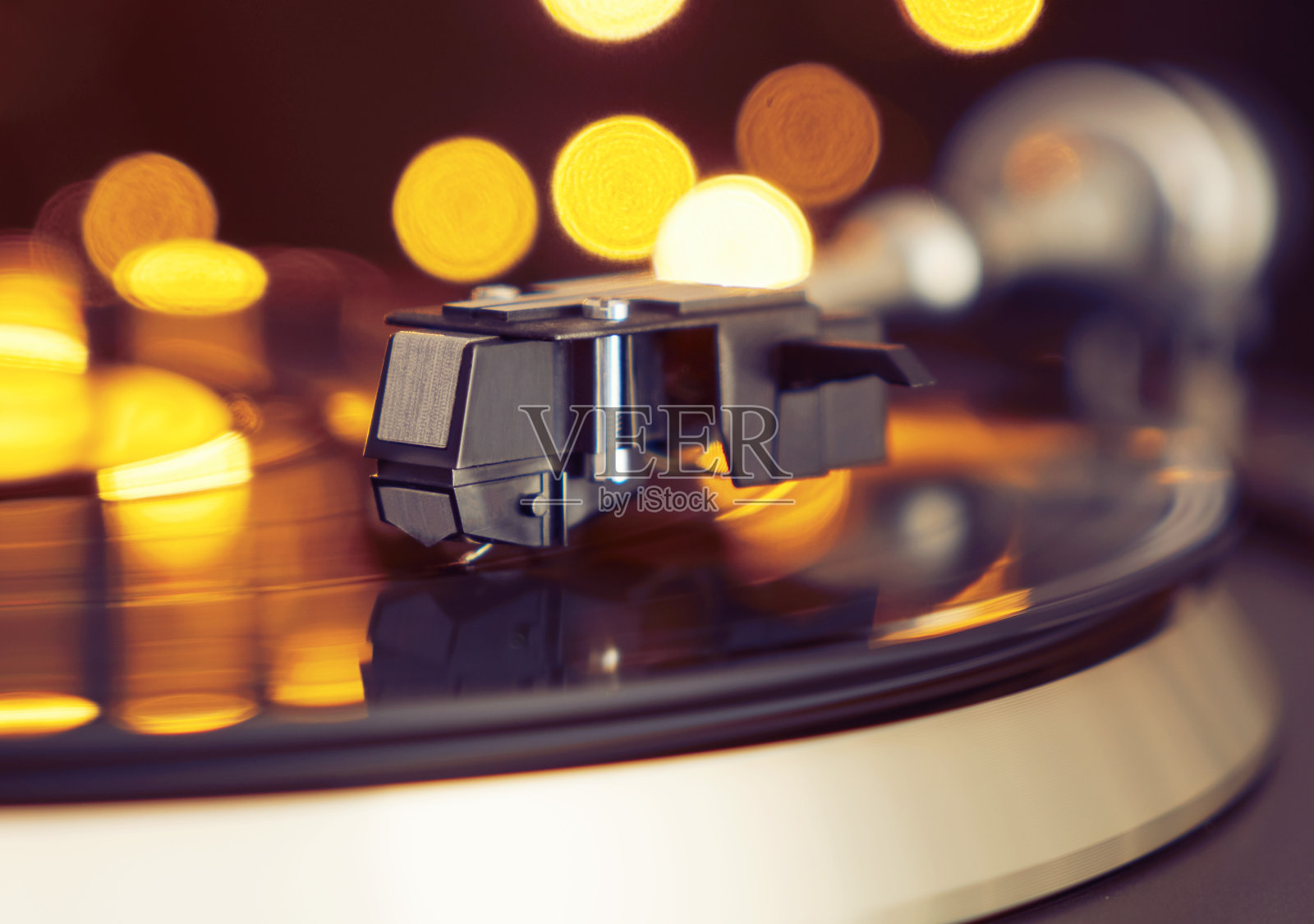 唱片机。音响技术为DJ混合和播放音乐。老式的黑胶唱片在一个派对的背景装饰，明亮的迪斯科散景灯。黑胶唱片上的针照片摄影图片