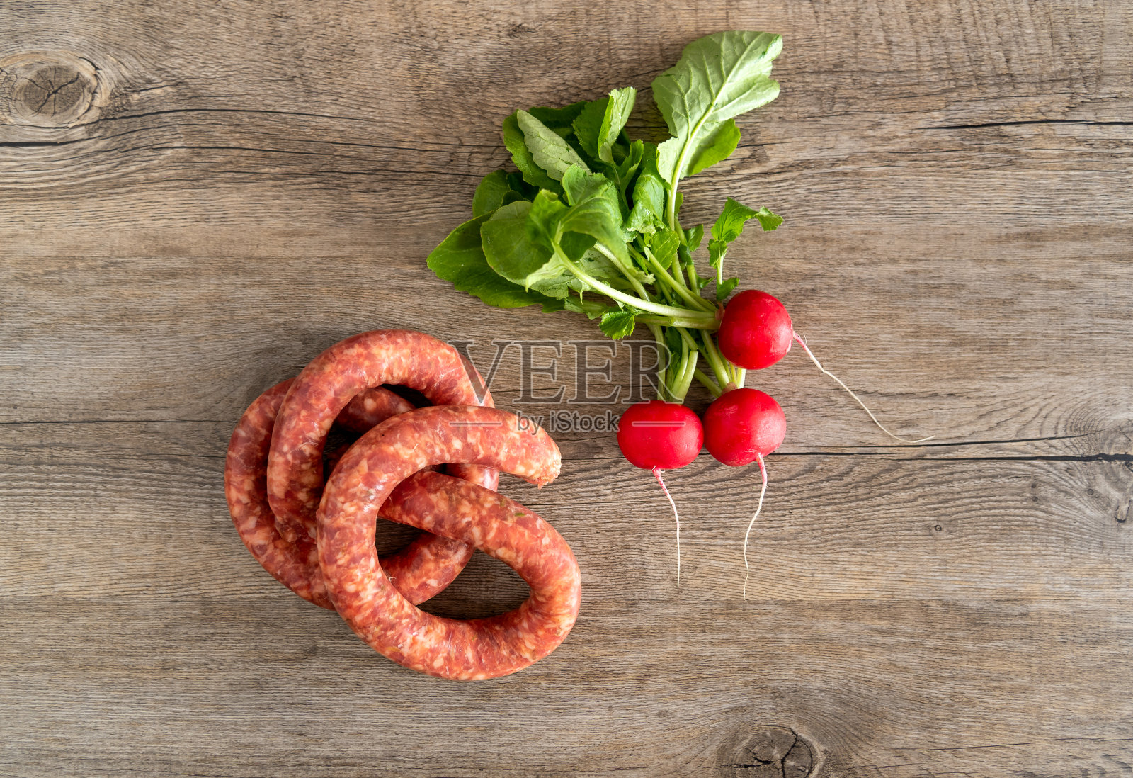 生猪肉香肠和萝卜在木制的乡村背景，俯视图。照片摄影图片