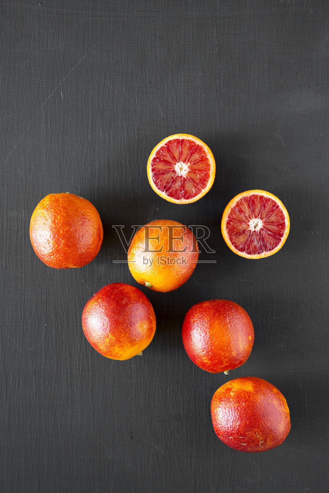 整个和减半的血橙在黑色的表面，俯视图。平躺着，从上面俯视。照片摄影图片