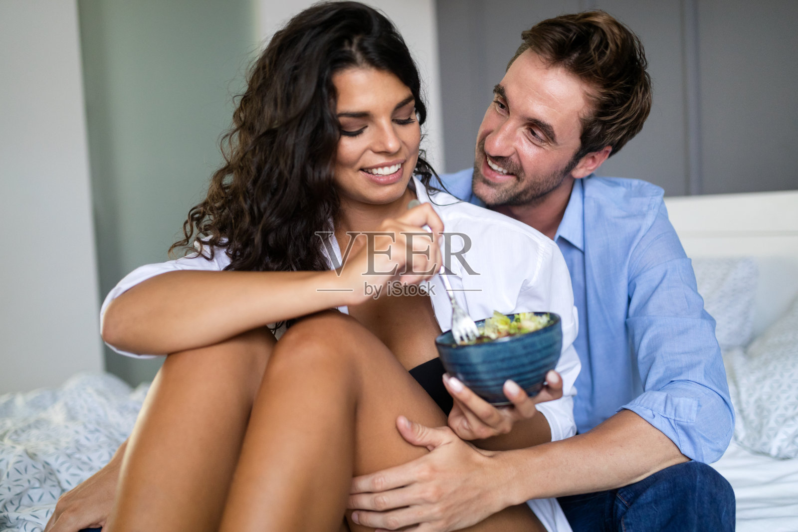 一对年轻夫妇在卧室的床上吃早餐照片摄影图片