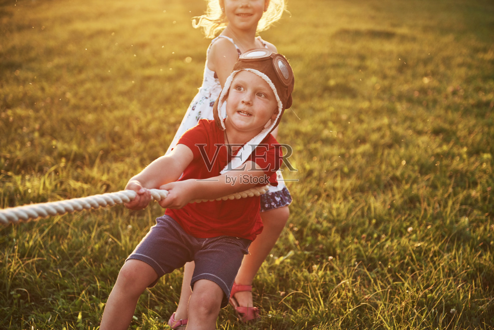 男孩和女孩在公园里拉绳子玩拔河游戏照片摄影图片