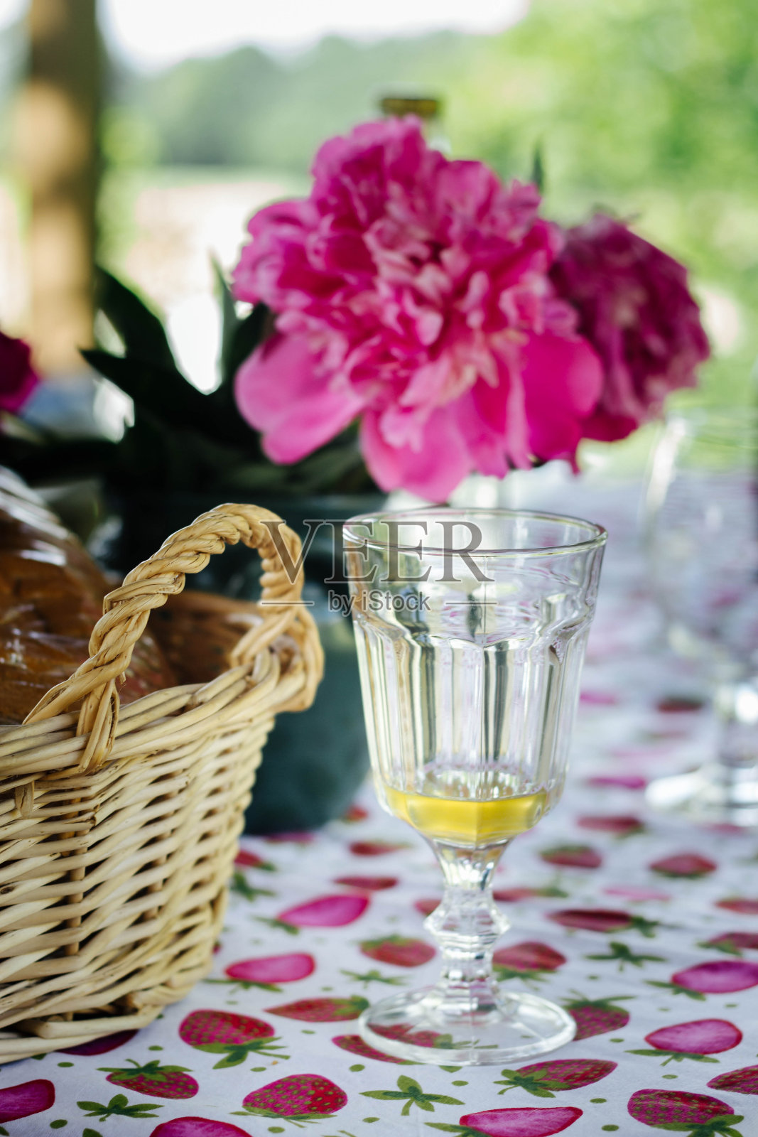 夏日游园会桌上有柳条篮子里的面包，可口的柠檬水和粉红色的牡丹照片摄影图片