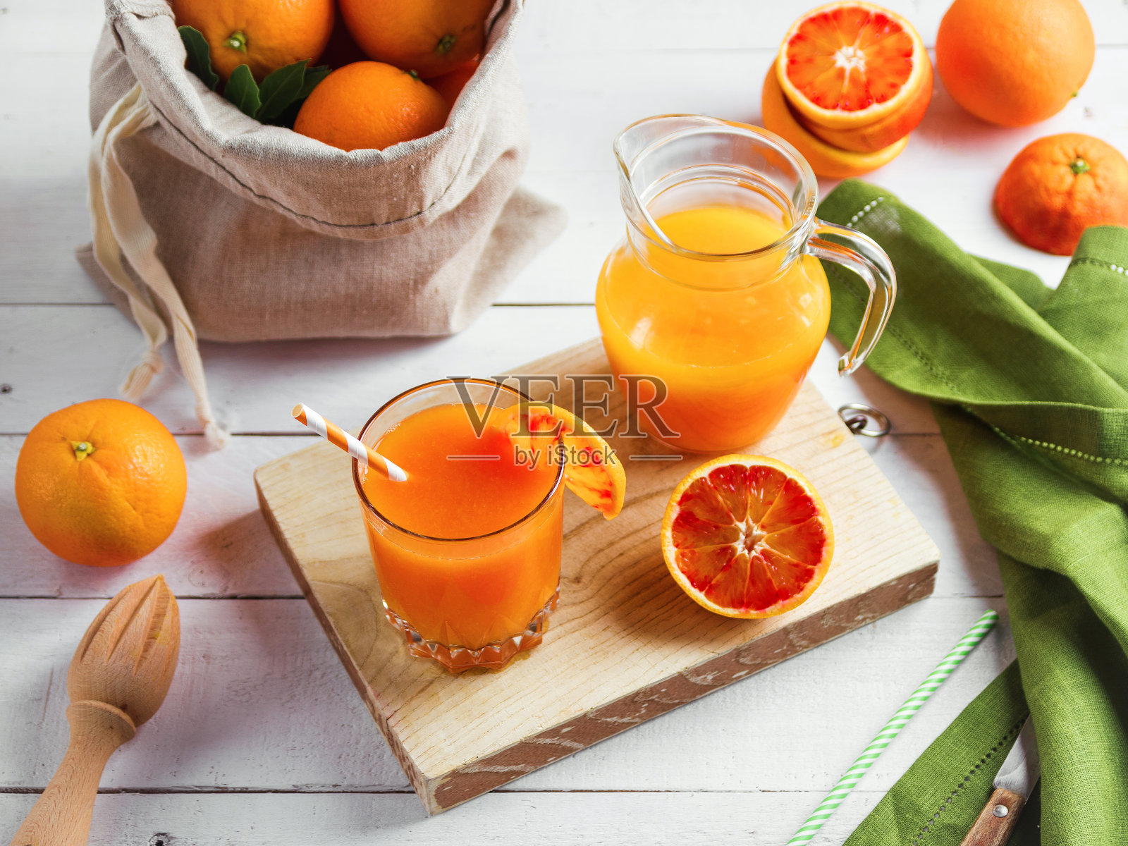 木桌上放着一杯新鲜榨橙汁和血橙。阳光明媚的夏日心情。照片摄影图片