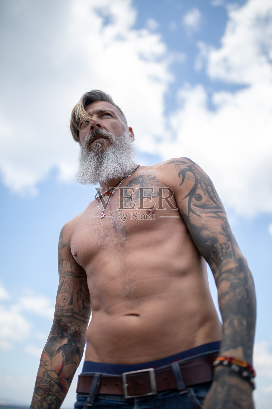 有魅力的胡子和纹身的成熟男子站在海滩上照片摄影图片