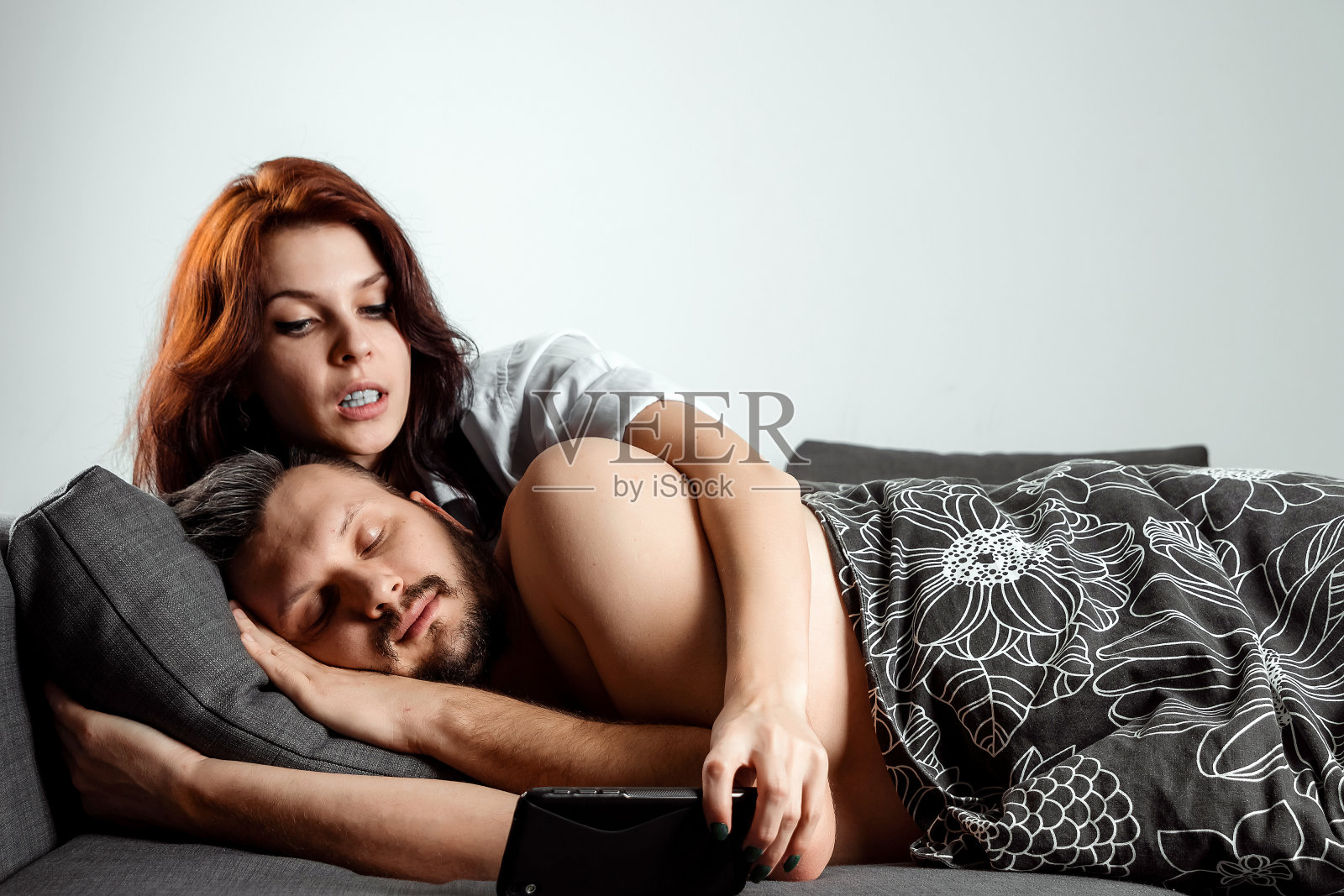 妻子在丈夫睡觉的时候偷看他的手机。不信任，背叛，嫉妒，关系，问题。照片摄影图片