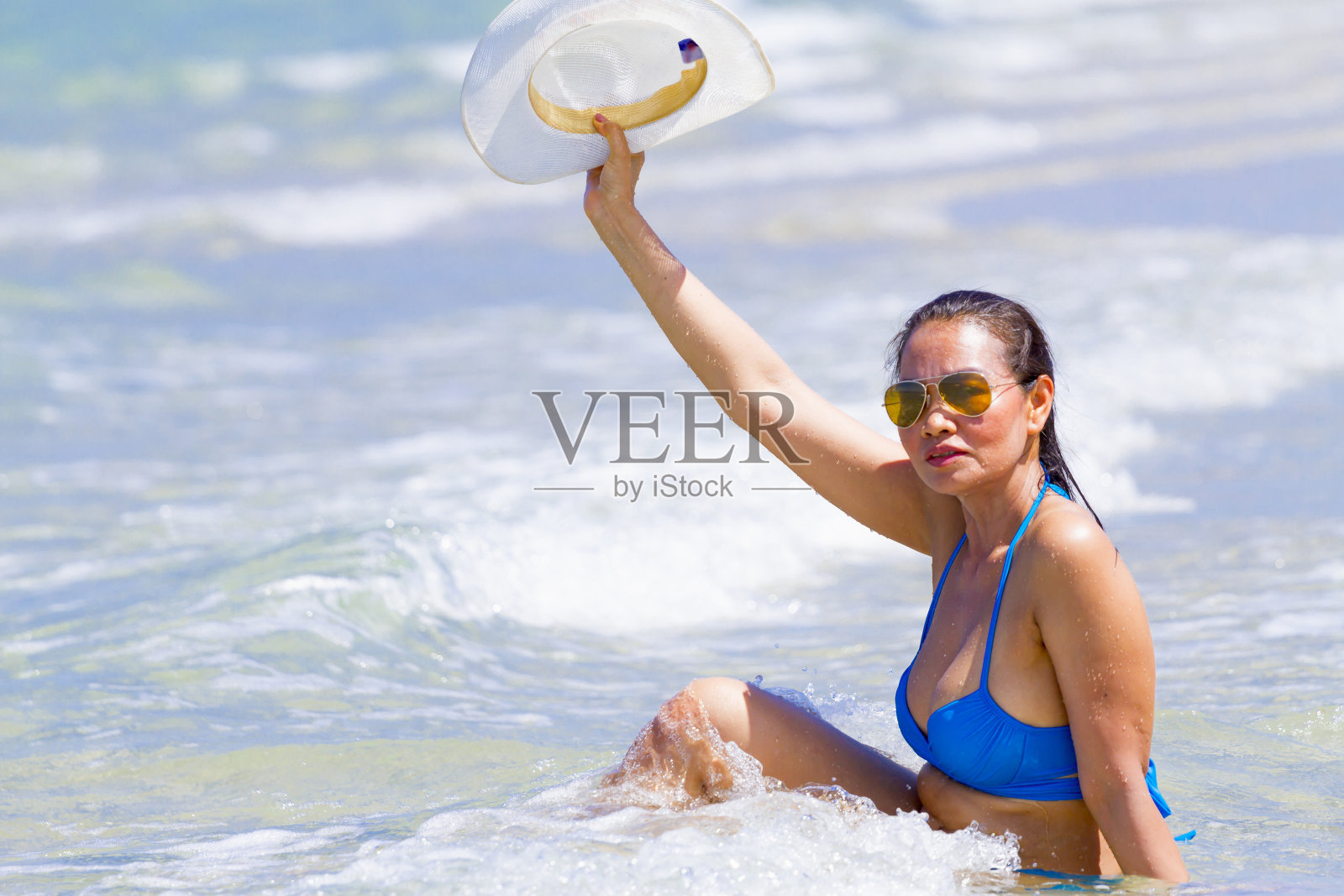 穿着蓝色比基尼和帽子的女人在海滩上波浪美丽照片摄影图片