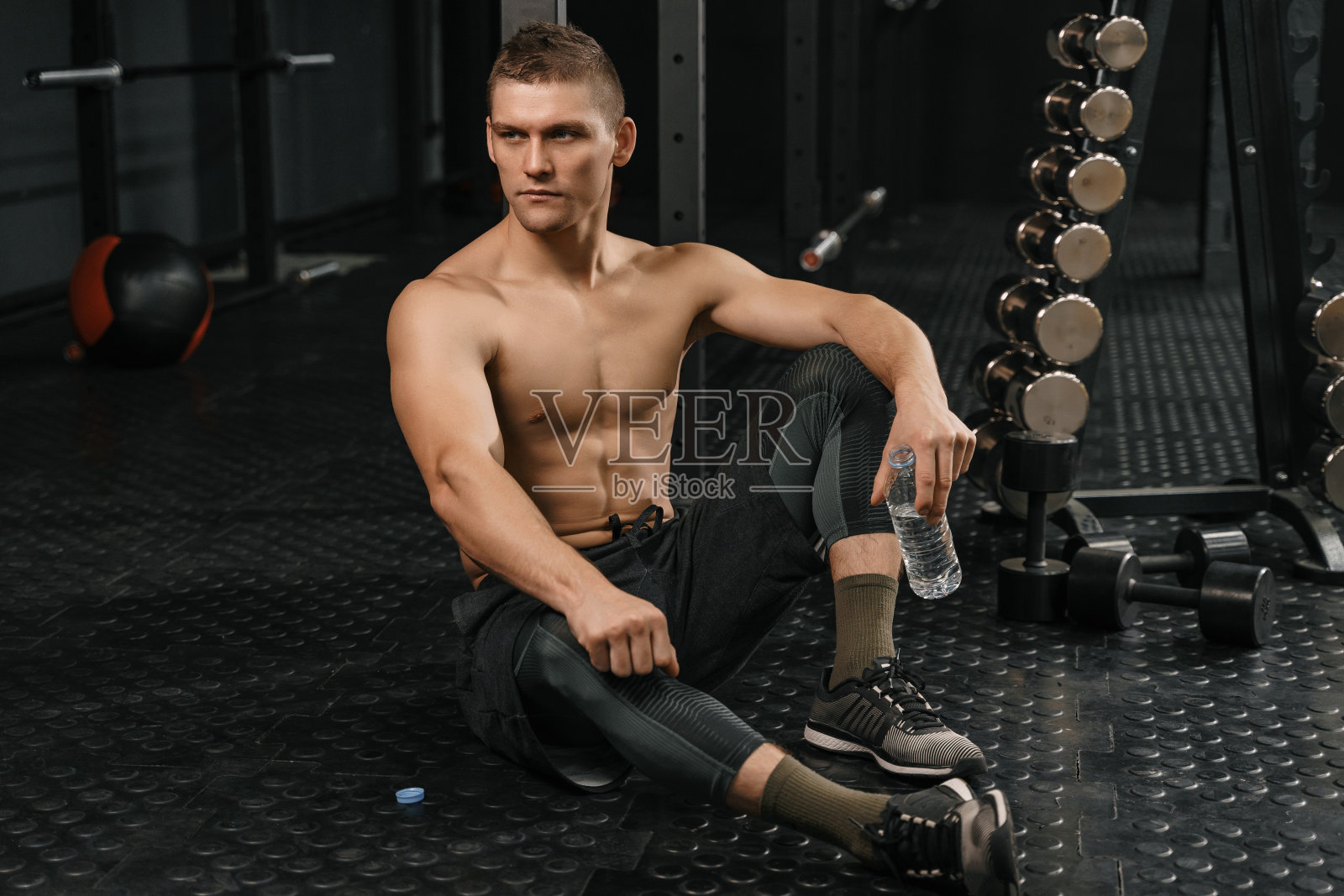 健身后休息：手持水瓶的年轻运动男士照片摄影图片