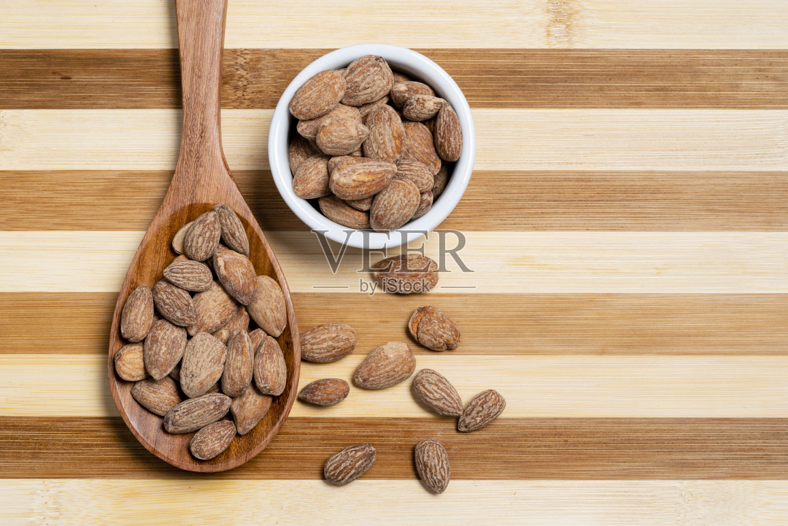 烤杏仁在木勺和竹条纹甜点锅照片摄影图片