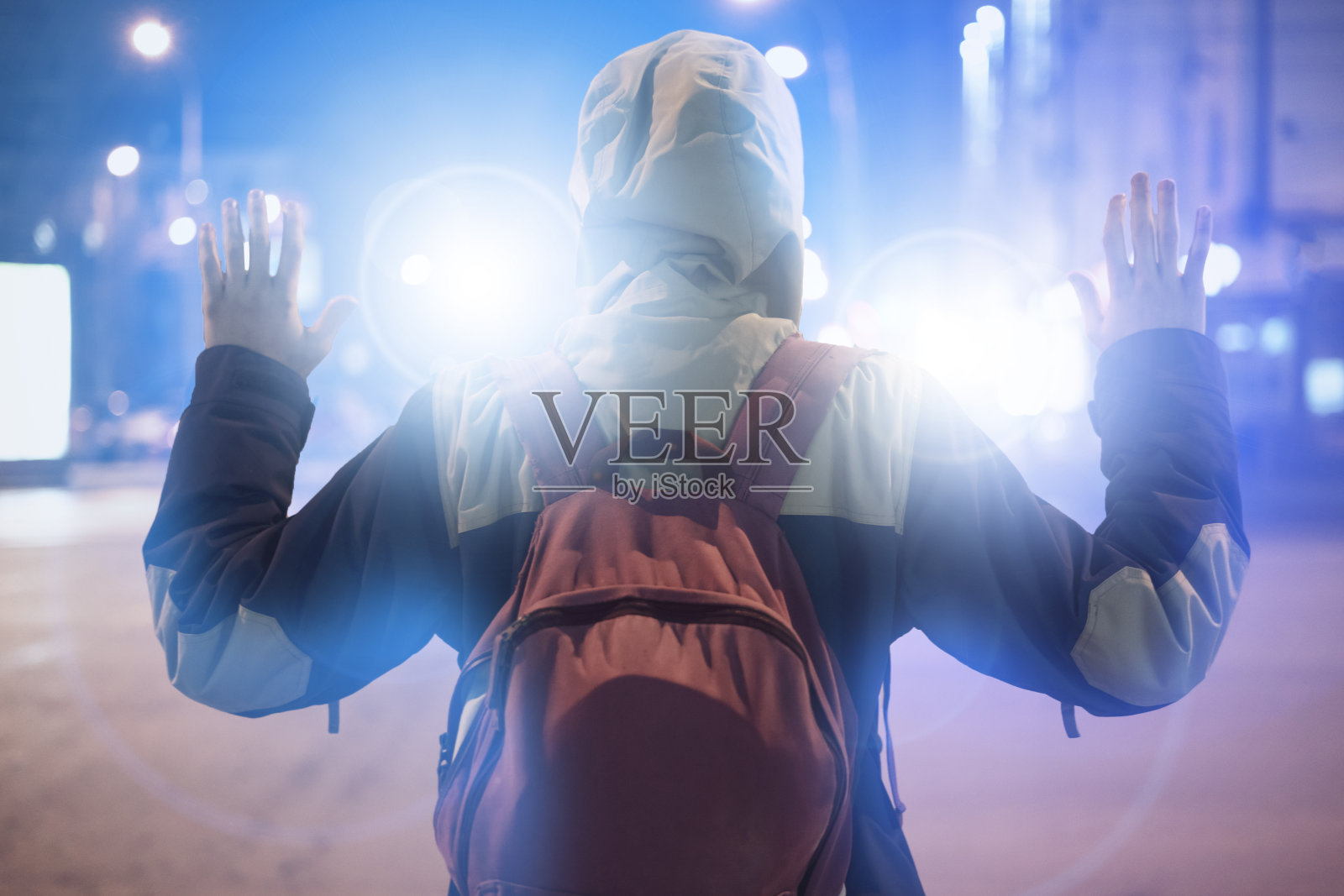 一名男性嫌犯在夜间被捕，身后有警察的闪光灯照片摄影图片