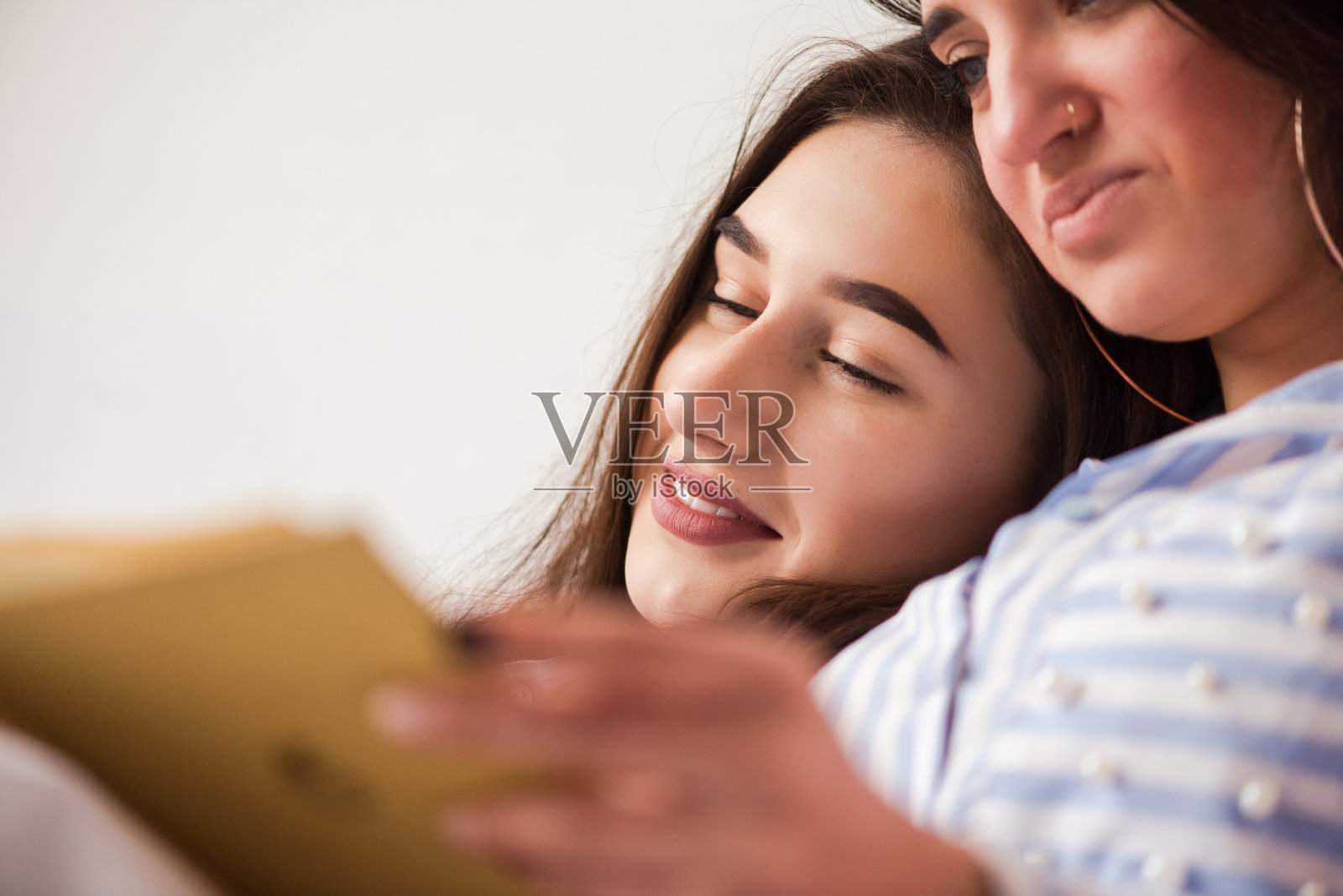 两个年轻女人在床上看书。照片摄影图片