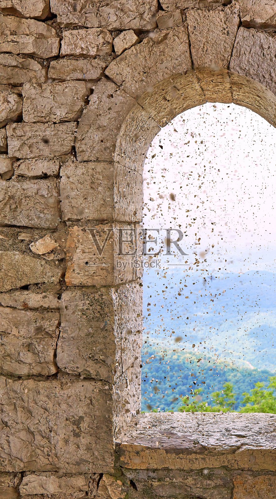 石头战塔窗户的纹理与运动模糊了鸟和海岸的景色与绿色的树山照片摄影图片