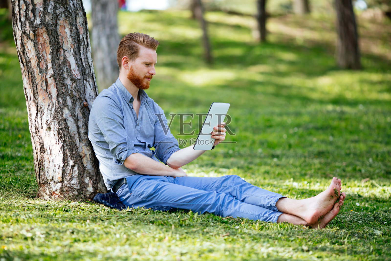 在公园里用平板电脑的帅气商人照片摄影图片