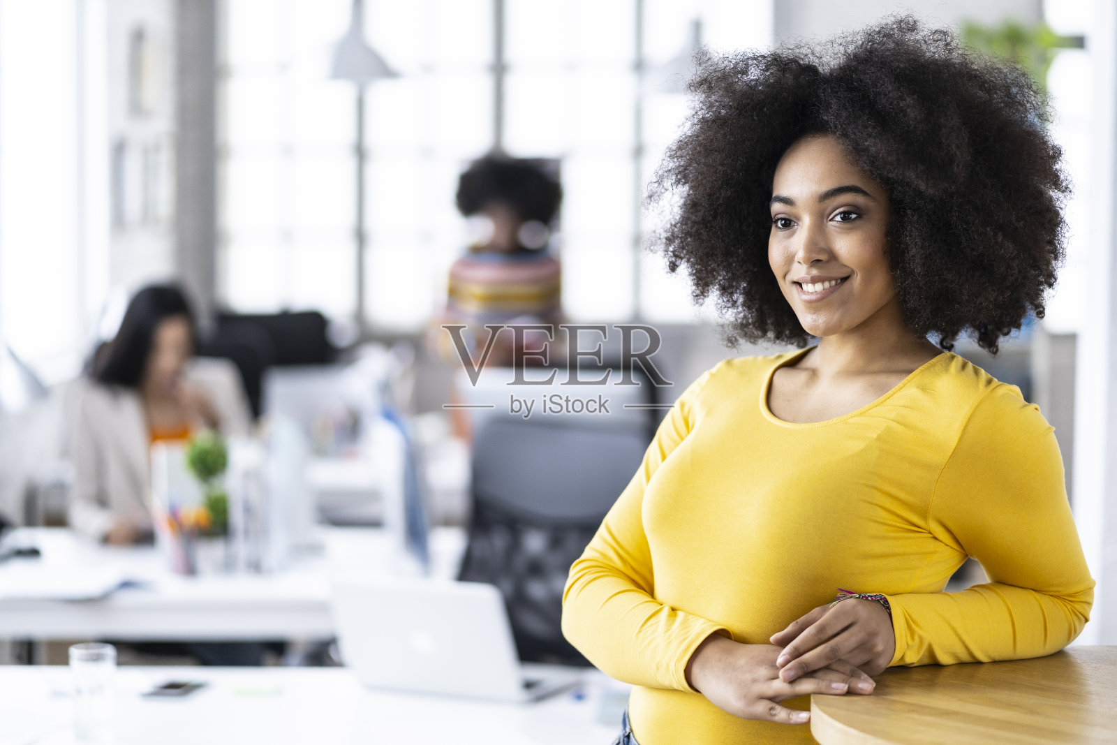 一个穿着黄色衣服的非洲妇女靠在桌子上照片摄影图片