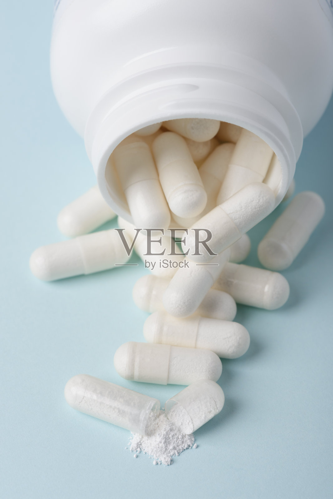 药丸从瓶子里溢出来，其中一个开了口，有白色物质照片摄影图片