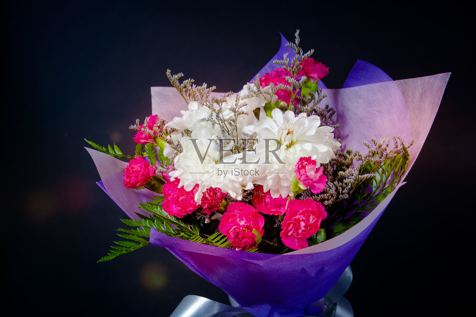 一束白色和红色的花，紫色的纸在黑色的背景照片摄影图片
