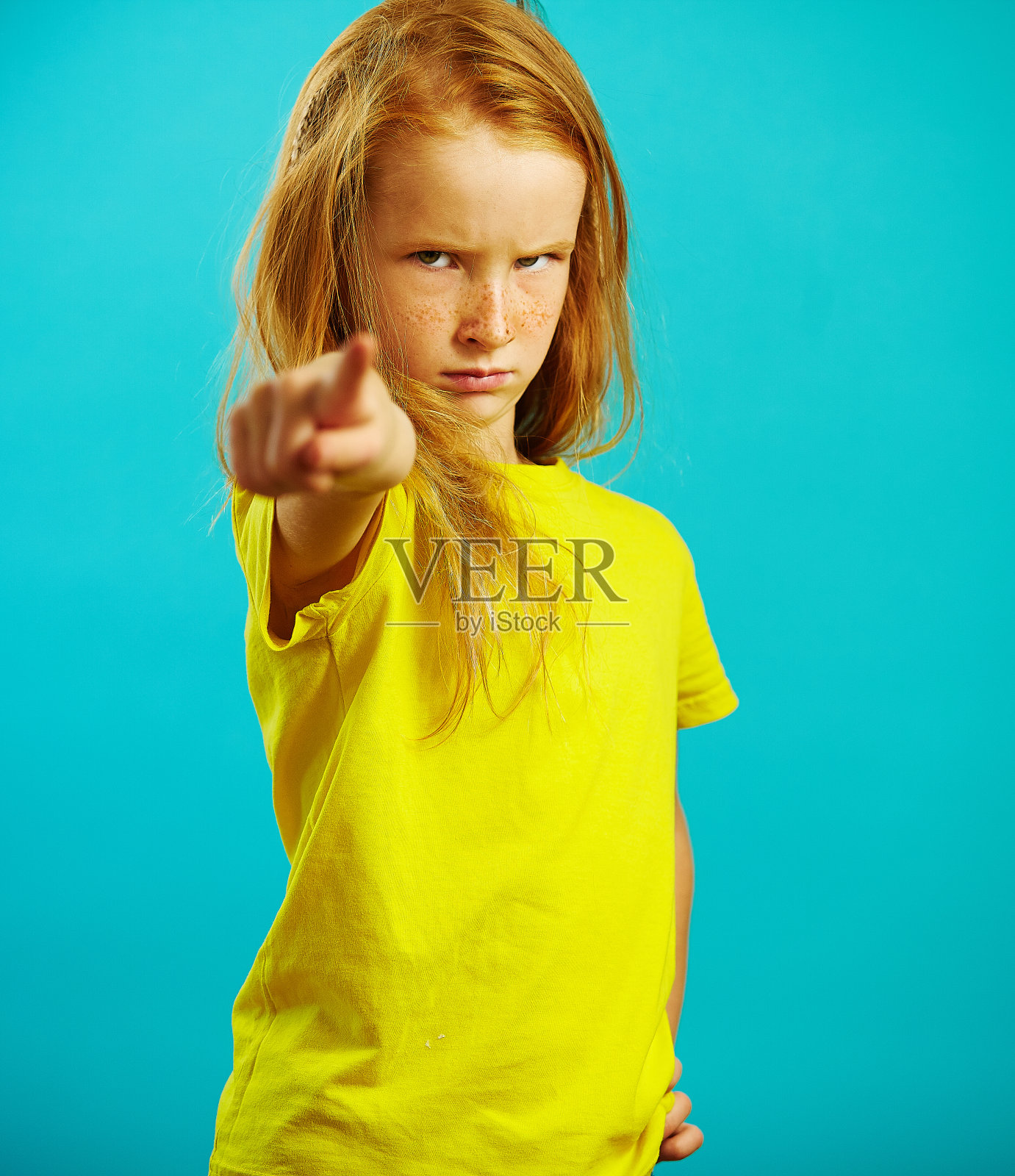 这张照片是一个红头发的小女孩指着你的手指，表情严厉而阴沉，表示心情不好，表现出严厉和愤怒。照片摄影图片