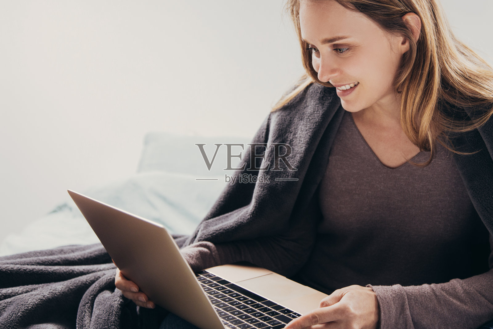 积极的年轻女子在卧室使用笔记本电脑照片摄影图片