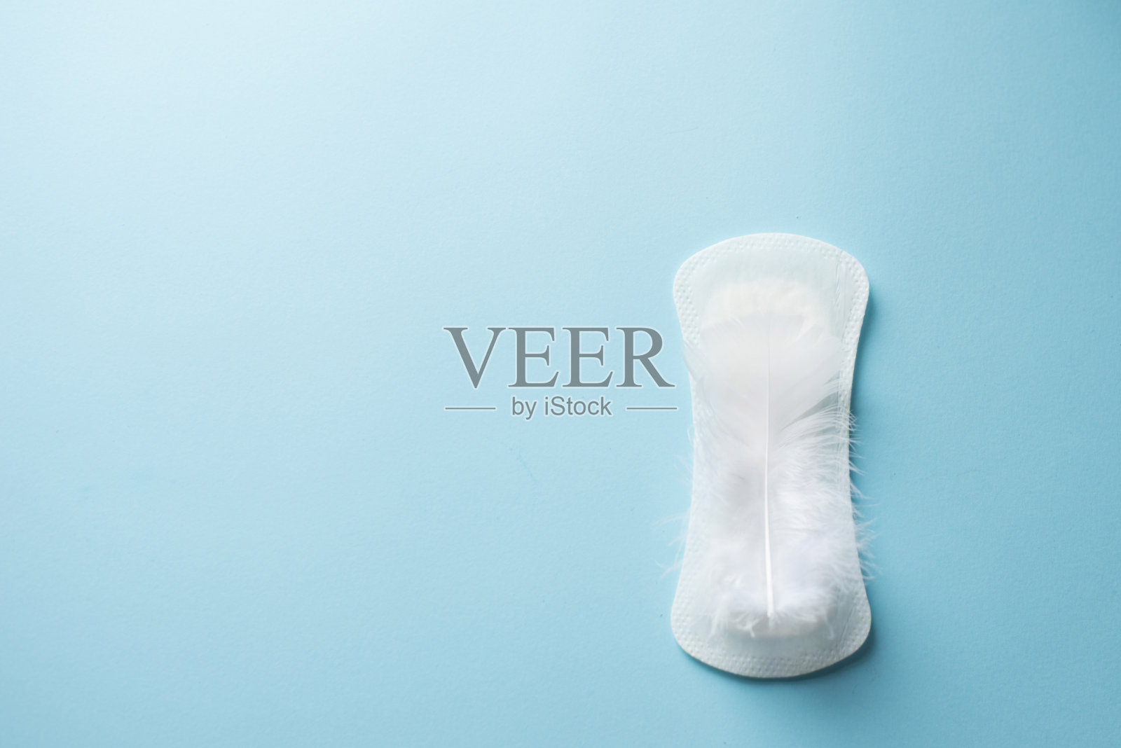 白色羽毛和日常，经期妇女卫生巾或血经期蓝色背景。副本的空间。妇女危急天数，妇科月经周期。医学概念图照片摄影图片