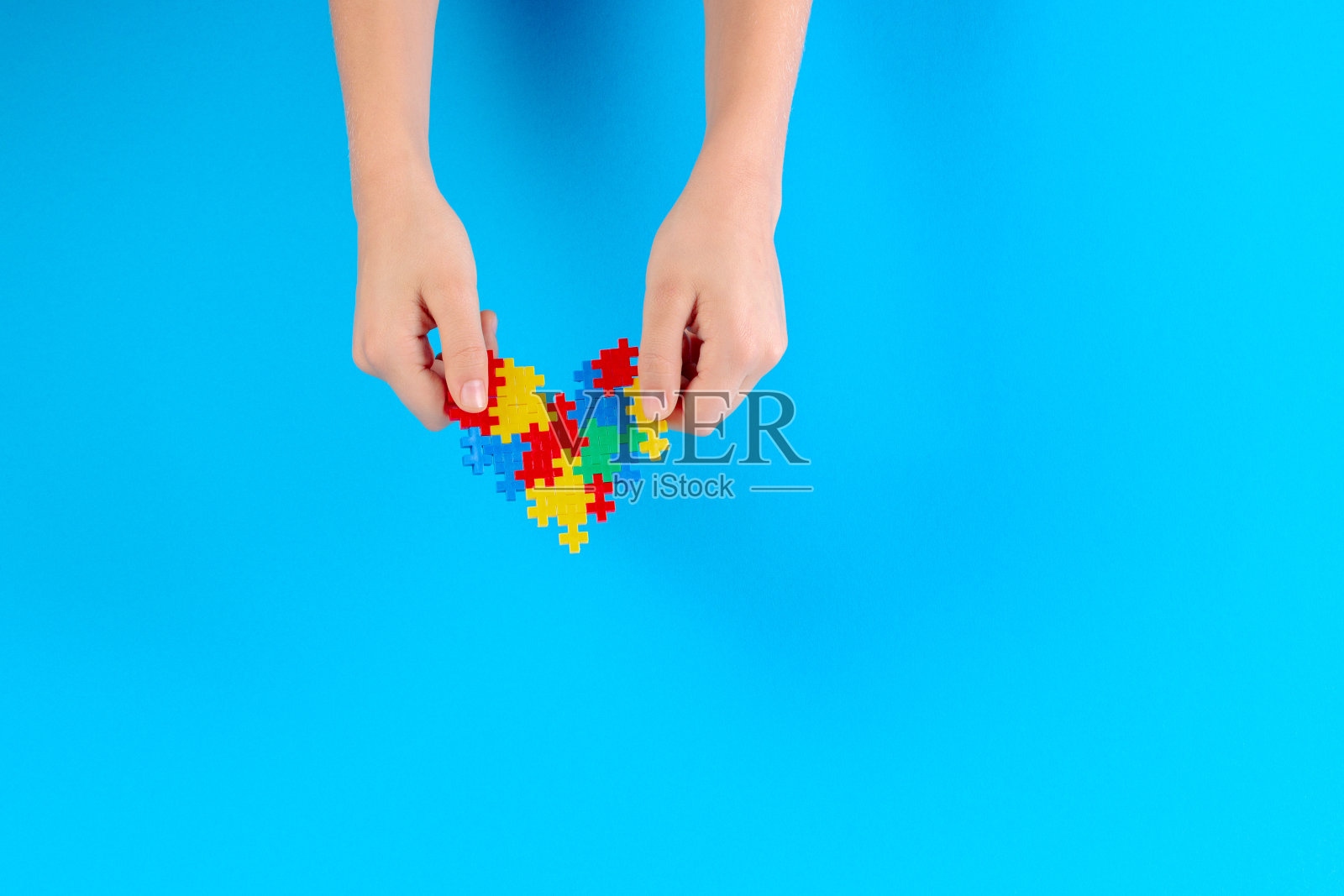 孩子手拿蓝色背景上的彩色心形，世界自闭症日概念照片摄影图片