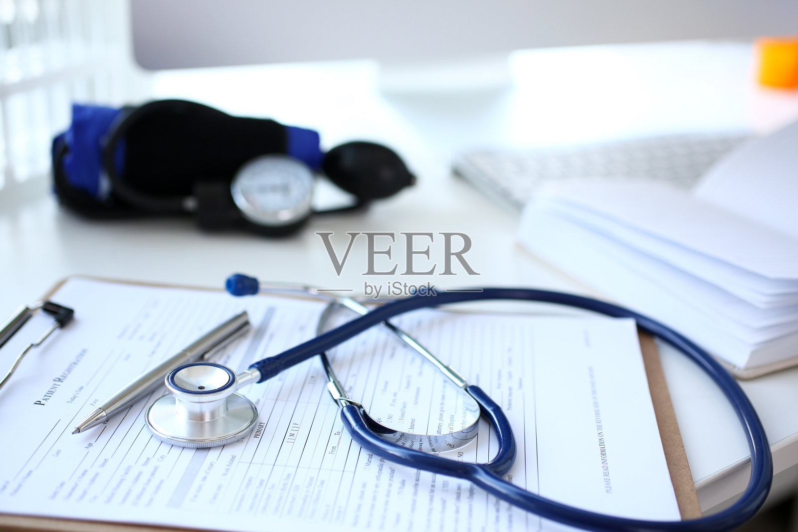 听诊器头和银笔躺在医疗申请表上照片摄影图片