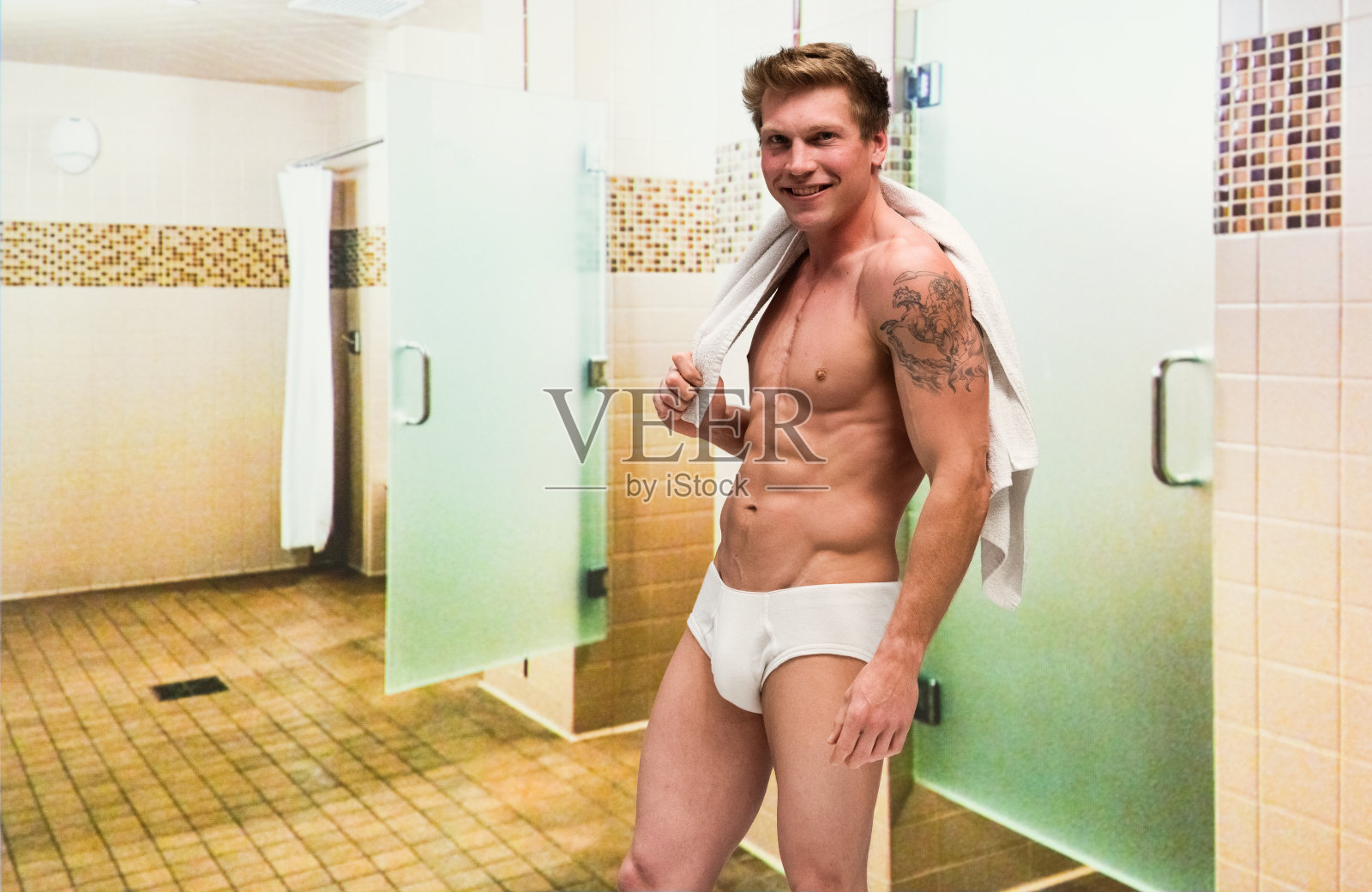 赤裸上身的帅哥穿着内裤拿着毛巾在健身房的更衣室里照片摄影图片