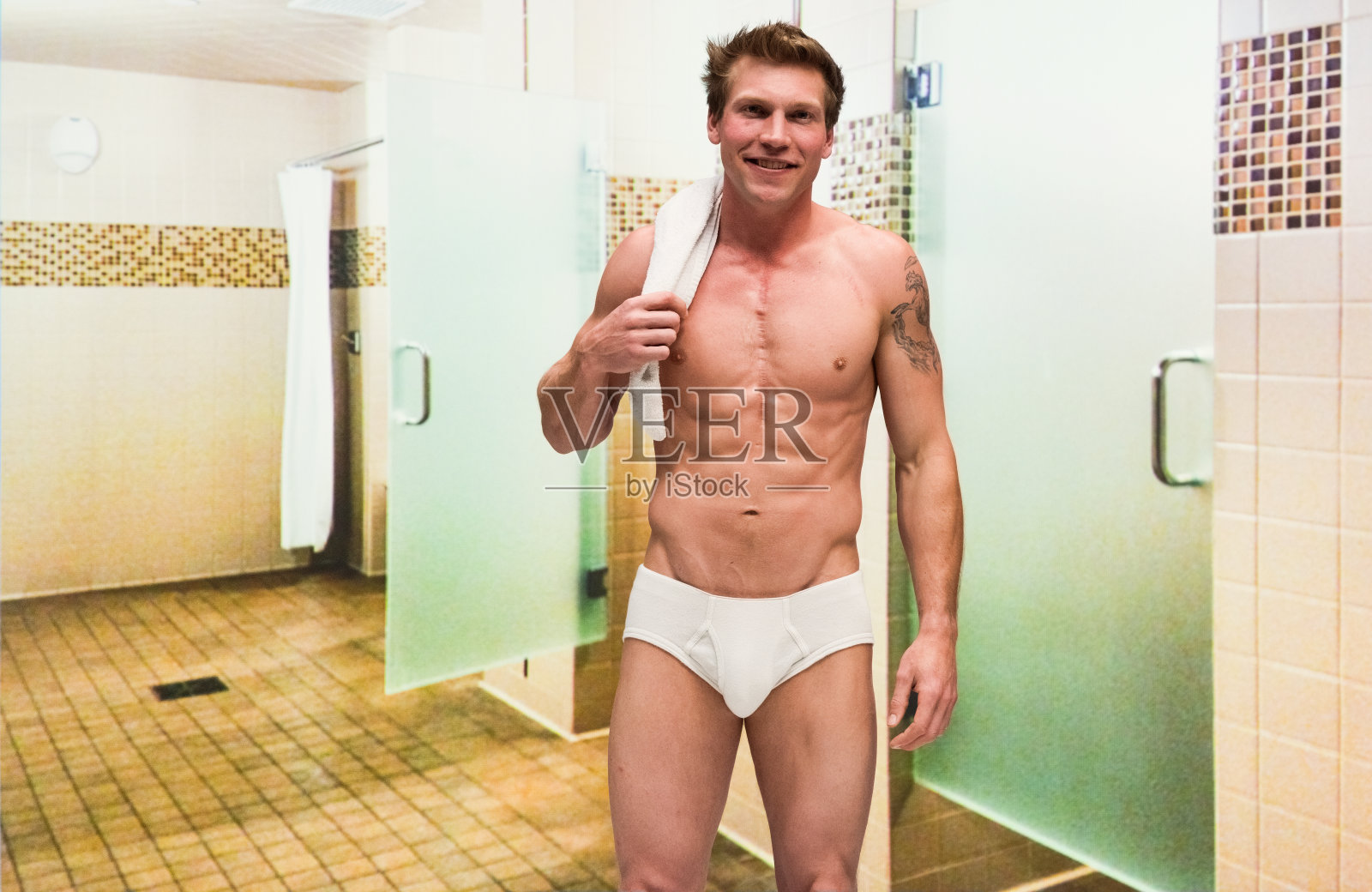 赤裸上身的帅哥穿着内裤拿着毛巾在健身房的更衣室里照片摄影图片