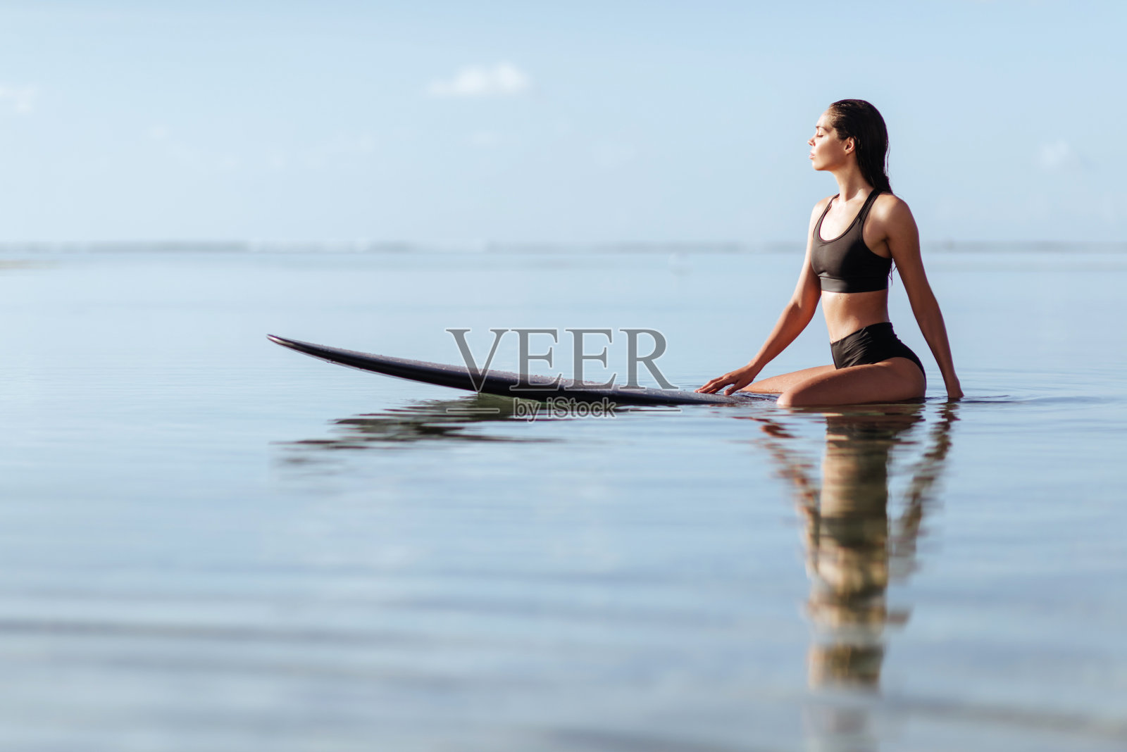 海里冲浪板上的漂亮女孩。照片摄影图片